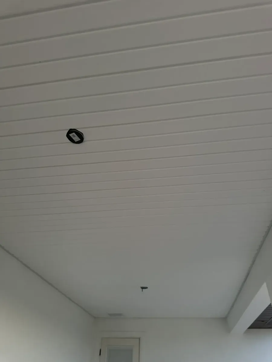 Interior soffit installation on covered porch - white horizontal panels with recessed lighting, new construction